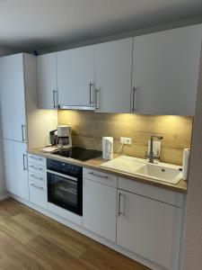 a kitchen with white cabinets and a sink at Ferienwohnung Sonnenblick in Hilzingen +2 photos