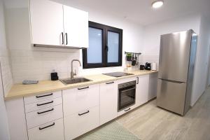 a kitchen with white cabinets and a stainless steel refrigerator at Arguineguin Sun Beach in Arguineguín