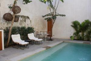 a pool with chairs and a table next to a building at MAYAPAN Mérida HiSTORIC CENTER in Mérida