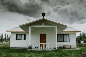 a white house with a table and chairs in front of it at Cabañas Altos del Volcán in Villarrica +3 photos