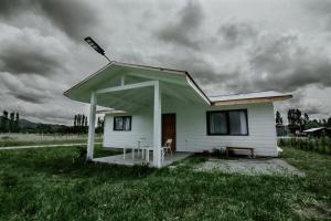 a small white house with a roof on a field at Cabañas Altos del Volcán in Villarrica