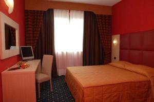 a hotel room with a bed and a desk and a window at Hotel Panorama in Cambiano