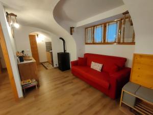 a living room with a red couch and an archway at alloggio in centro con giardino in Sampeyre