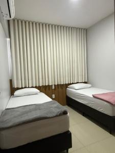 two beds in a room with a window at Apartamento bem localizado perto de tudo - 3 quartos em Belém in Belém +33 photos