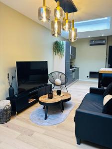 a living room with a black couch and a table at Élégant appartement avec bain balnéothérapie in Liège