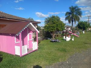 una capanna rosa in un cortile con parco giochi di Hotel El-Shaday a Vila Nova do Sul