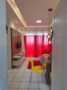 una sala da pranzo con tende rosse, tavolo e sedie gialle di Apartamento para temporada Beira Mar a Fortaleza