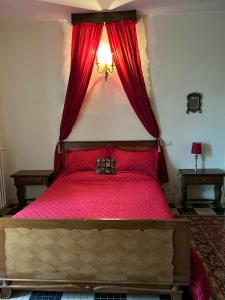 a bedroom with a red bed with red curtains at Manoir de Manapany in Angliers