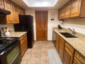 a kitchen with wooden cabinets and a black refrigerator at Snowed Inn in Brian Head +12 photos