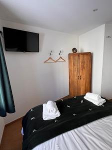 a bedroom with a bed with a tv and towels at Les Fermes de Cal Panche Le Petit Relais in Les Angles