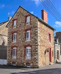 an old brick building with red windows on a street at La villa Alixel in Pléneuf-Val-André
