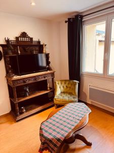 a living room with a television and a chair at Les Fermes de Cal Panche Le Petit Relais in Les Angles