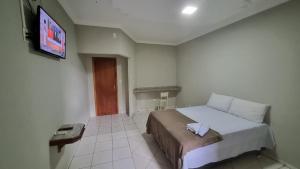 a bedroom with a bed and a flat screen tv at Hotel do Vale in Juscimeira