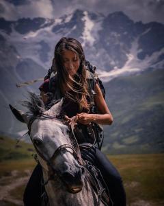 una mujer montada en el lomo de un caballo en Ushguli Cabins, en Ushguli