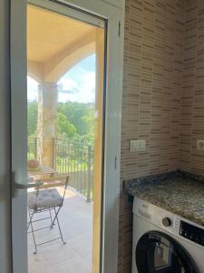 a kitchen with a washer and a balcony with a table at Nature House in Maçanet de la Selva