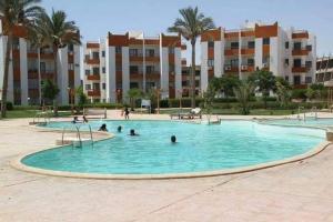 a swimming pool with people in it in front of a building at شاليهات قرية هوليداى فانتازيا in Ras Sedr