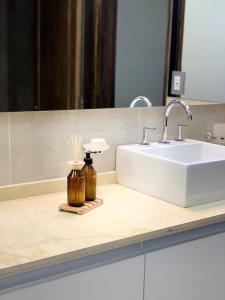 Un mostrador de baño con un lavabo y un espejo. en Laprida Suites 1 San Juan, en San Juan