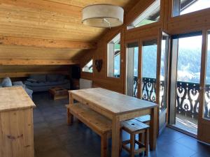 a room with a table and a couch and windows at Chalet Fleur des Alpes 2 in Les Gets