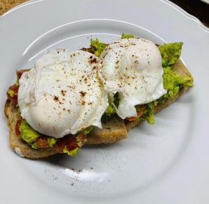 two eggs on top of a sandwich on a white plate at The Pathway Guesthouse in Whitby