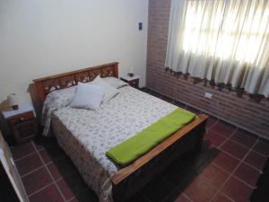 a bedroom with a bed with a green blanket on it at Cabañas los amigos Tala in Potrero de Garay