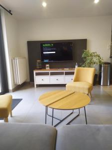 Una sala de estar con televisión, mesa y sillas. en La Loge Bertine France, en Saint-Mars-la-Réorthe