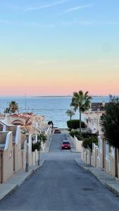 eine Straße mit Autos, die eine Straße entlang des Ozeans fahren in der Unterkunft CASA Adosada obra nueva Calas santa pola del este 50 metros del mar in Santa Pola