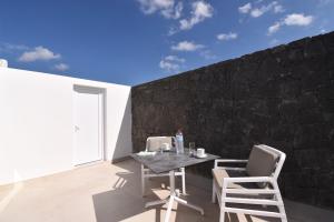 a patio with a table and chairs and a wall at Nicole Home in Playa Blanca