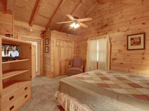 une chambre avec un lit et un ventilateur de plafond dans l'établissement 1BR log cabin- cozy, hot tub, in Gatlinburg, à Gatlinburg