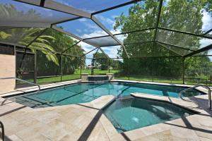 an indoor swimming pool with a large glass wall at New lanai! Electric-heated pool home with spa in quiet neighborhood - Villa Milano in North Fort Myers