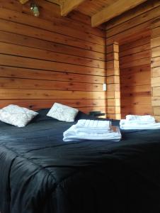 a bedroom with a black bed with wooden walls at Pizarra Escondida in El Chalten