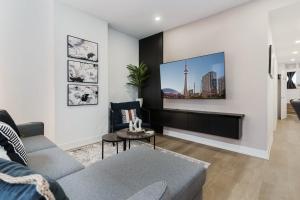 トロントにあるModern Suite 3 min to Transit Downtown Torontoのソファと壁掛けテレビのあるリビングルーム