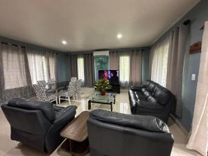 a living room with black leather furniture and a tv at Anas place Siusega in Vaitele