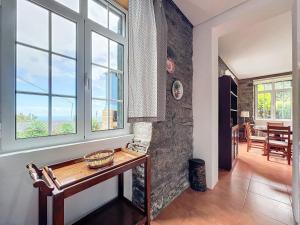 ein Wohnzimmer mit einem Tisch und Fenstern in der Unterkunft Quinta do Serrado in Porto Moniz