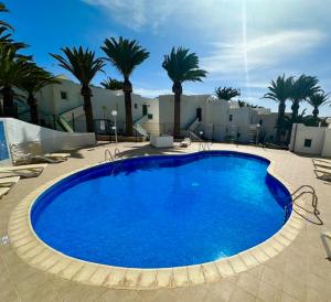 a large blue pool with palm trees and buildings at Casa del Capitan in Costa Calma