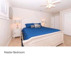 a bedroom with a bed with blue sheets and a ceiling fan at Thumb Point Oasis w Heated Pool walk to beach in Fort Pierce +28 photos
