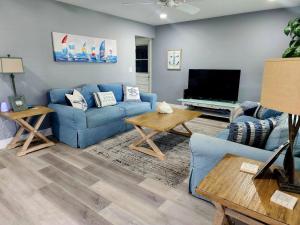 a living room with a blue couch and a tv at Serene Cottage in Stuart in Stuart