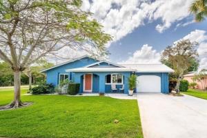 a blue house with a tree in the yard at Serene Cottage in Stuart in Stuart