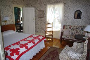 a bedroom with a bed and a chair and a window at The Garrison House Inn in Annapolis Royal