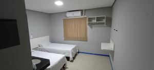 a small room with two beds and a window at Brasil hotel in Canaã dos Carajás