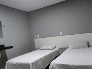 two beds in a room with white walls at Brasil hotel in Canaã dos Carajás