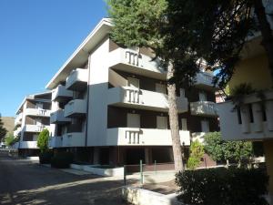 um edifício de apartamentos branco com uma árvore em frente em Gemma 3 Pineto Vacanza em Pineto