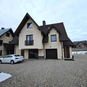 una casa con un coche aparcado en una entrada en Grafitowe Apartamenty, en Czarna Góra