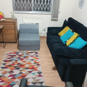 Sofa cama em sala adaptada com Ar condicionado في ريو دي جانيرو: غرفة معيشة مع أريكة وكرسي +صورة واحدة