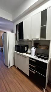 a kitchen with white cabinets and a refrigerator at Apartamento completo no Centro de Nova Friburgo in Nova Friburgo