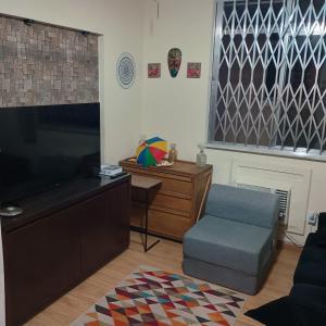 Sofa cama em sala adaptada com Ar condicionado في ريو دي جانيرو: غرفة معيشة مع تلفزيون وكرسي