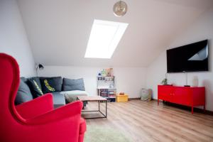 ein Wohnzimmer mit einem roten Stuhl und einem TV in der Unterkunft Quiet Apartment - 74qm - 2 Bedrooms - 3 Beds in Limburg an der Lahn