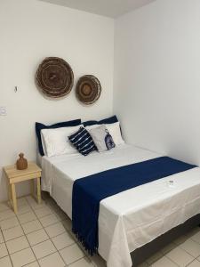 a bedroom with a bed with blue and white sheets at Flat Brisa da BARRA in Barra de São Miguel +5 photos