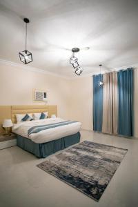 a bedroom with a bed with blue curtains and a rug at Hayatt Ula Suite - 104 in AlUla