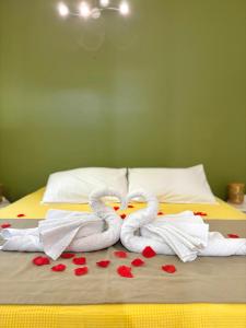two towel swans sitting on a bed with hearts at Gîte Mabouya - Hamac, Piscine, Jardin in Anse-Bertrand