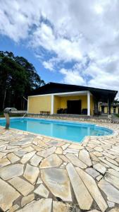 a swimming pool with a stone floor and a building at Sítio embeleze ou Dois irmãos in Juquitiba